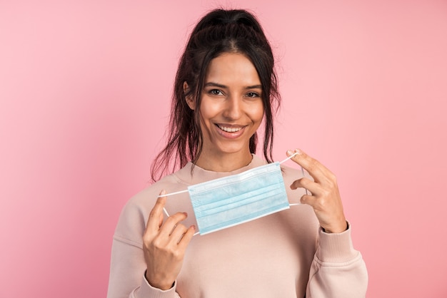 Jolie fille attrayante tient un masque protecteur dans ses mains et le met.