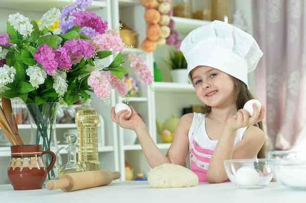 Jolie fille au chapeau de chefs faisant de la pâte