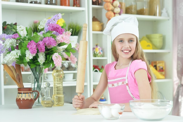 Jolie fille au chapeau de chefs faisant de la pâte