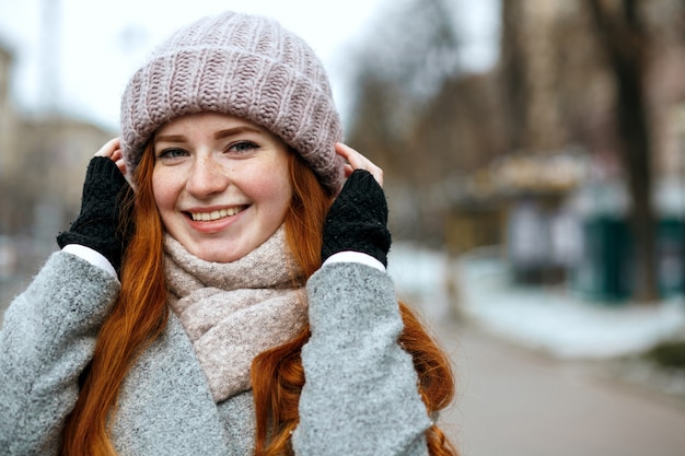 Jolie fille au gingembre aux cheveux longs portant un bonnet tricoté