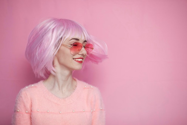 Jolie fille aux cheveux roses tourne la tête sur le côté et sourit les cheveux courts et délicats volent