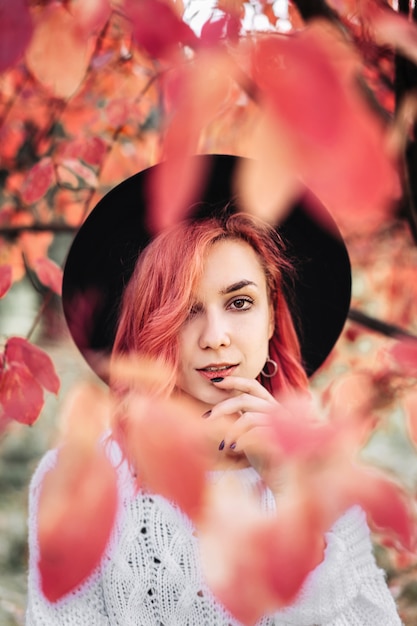 Jolie fille aux cheveux rouges et chapeau marchant dans le parc, temps d'automne.