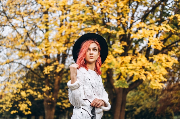 Jolie fille aux cheveux rouges et chapeau relaxant dans le parc, temps d'automne.