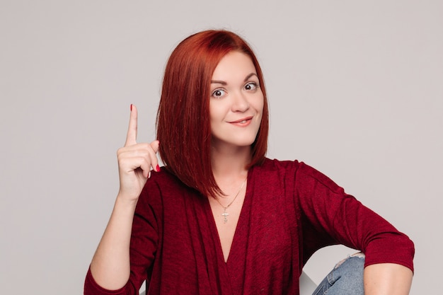 Jolie Fille Aux Cheveux Rouges En Chemisier Bordo Et Jeans Pense à Quelque Chose.