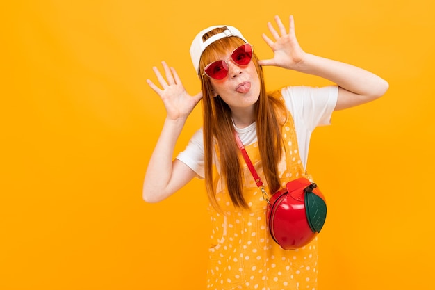 Jolie fille aux cheveux rouges posant sur des sourires de caméra avec petit sac de pomme isolé sur fond jaune.