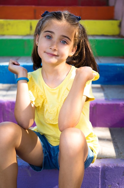 Jolie fille aux yeux bleus avec un visage heureux parce qu'elle retourne à l'école. sur un escalier coloré