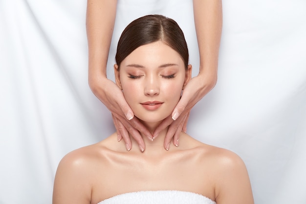 Photo jolie fille ayant un massage pour son cou allongé sur blanc