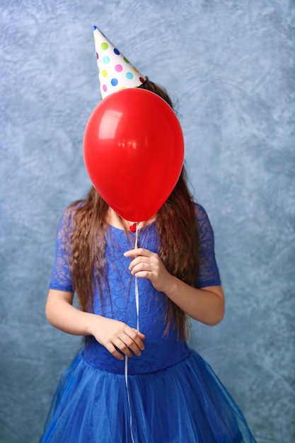 Jolie fille avec ballon de couleur sur une surface grise