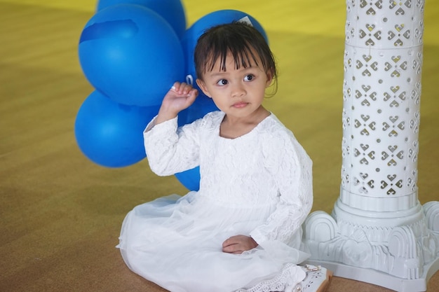 Une jolie fille avec des ballons assise sur le sol en bois dur