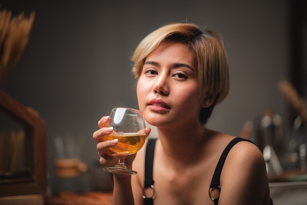 Jolie fille de barman tenant dans ses mains un cocktail frais au comptoir du bar pour la célébration