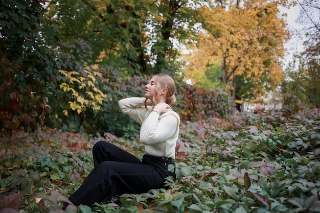 Jolie fille avec une belle coiffure est assise dans le jardin les yeux fermés