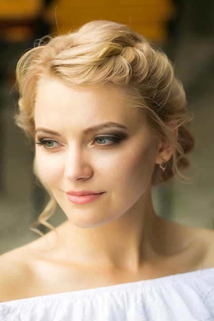 Jolie fille belle femme blonde avec une coiffure élégante en robe blanche à l'extérieur le jour d'été ensoleillé