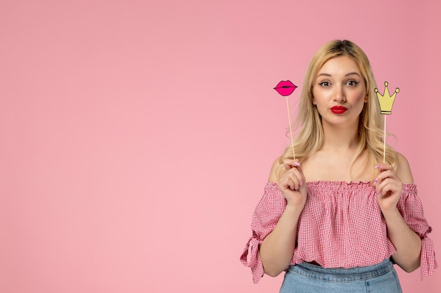 Jolie fille belle jeune femme avec du rouge à lèvres en chemisier rose tenant la couronne et les lèvres