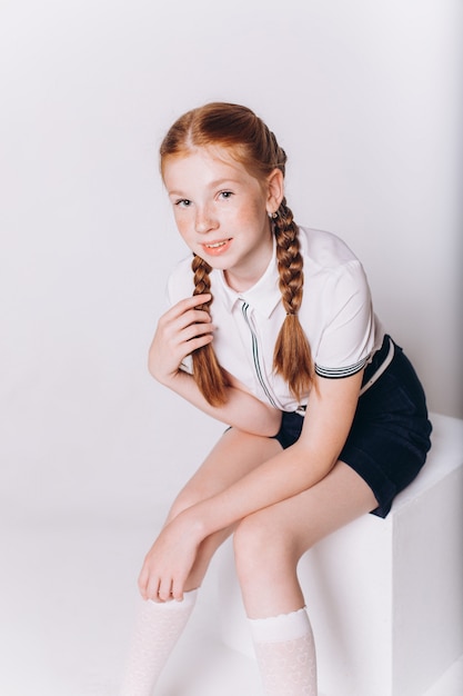 Jolie fille blonde adorable caucasienne en uniforme scolaire sur fond blanc