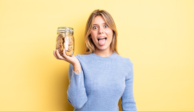 jolie fille blonde avec une attitude joyeuse et rebelle, plaisantant et tirant la langue. concept de biscuits faits maison