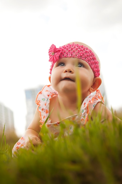 Jolie fille blonde aux yeux bleus heureuse de 6 à 7 mois rampant sur l'herbe et levant les yeux. Photo conceptuelle pour l'éducation, l'enfance en bonne santé, la parentalité. Bébé caucasien parfait. Mise au point sélective