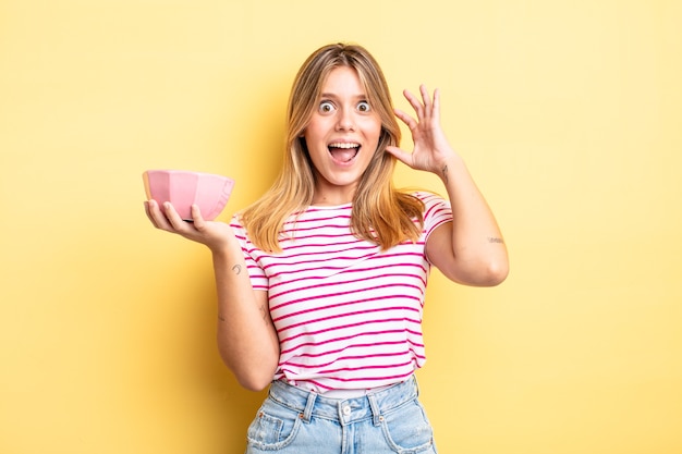 Jolie fille blonde criant avec les mains en l'air. concept de bol vide