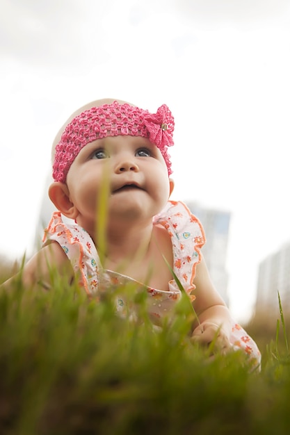 Jolie fille blonde heureuse aux yeux bleus de 8 mois dans l'herbe