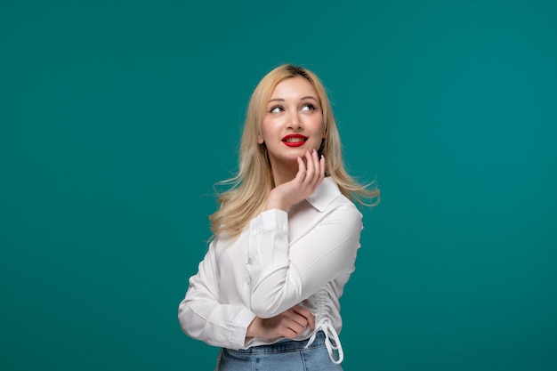 Jolie fille blonde jeune jolie fille dans une chemise blanche levant les yeux et rêvant avec la main sur le visage