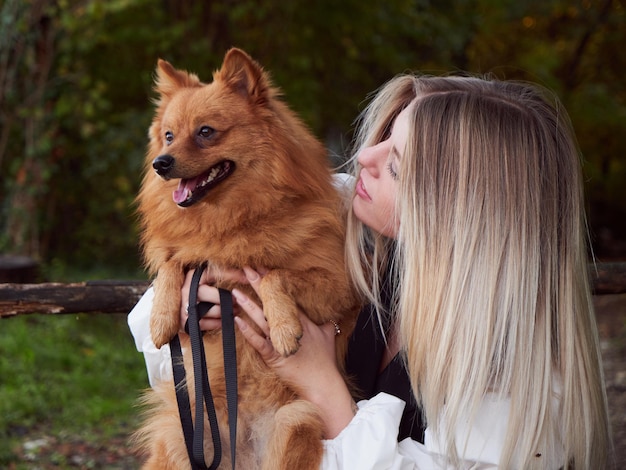 Jolie fille blonde joue avec un chien de Poméranie