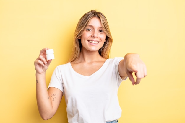 jolie fille blonde pointant vers la caméra en vous choisissant. concept de bouteille de pilules