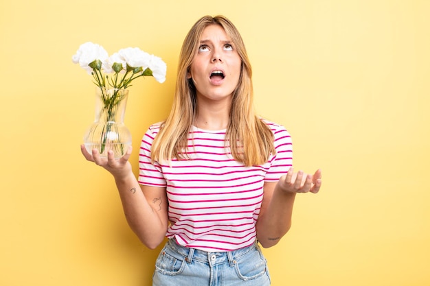 Jolie fille blonde qui a l'air désespérée, frustrée et stressée. concept de fleurs décoratives