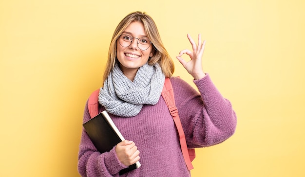 Jolie fille blonde se sentant heureuse, montrant son approbation avec un geste correct. concept d'étudiant