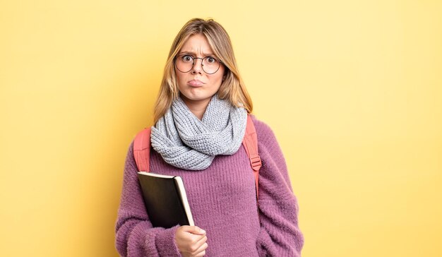 Jolie fille blonde se sentant triste et geignarde avec un regard malheureux et un concept d'étudiant qui pleure