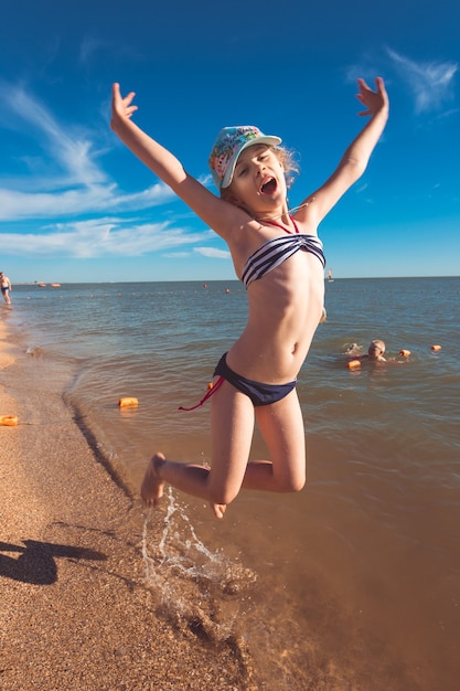 Jolie fille blonde de sept ans s'amusant et s'amusant à la mer pendant les vacances.