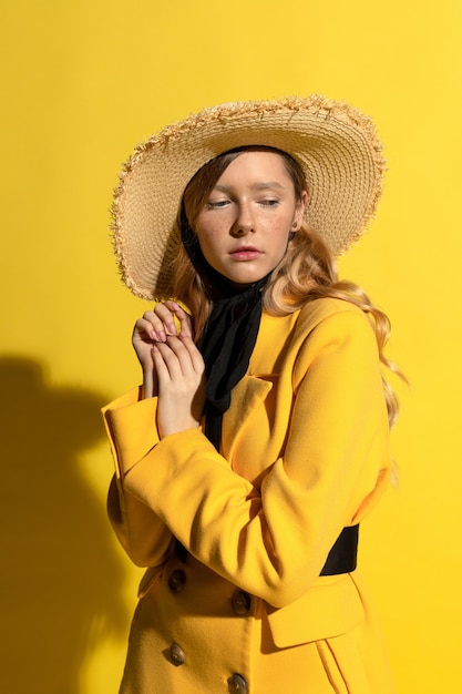 Jolie fille blonde avec des taches de rousseur en tenue jaune et chapeau de paille sur jaune