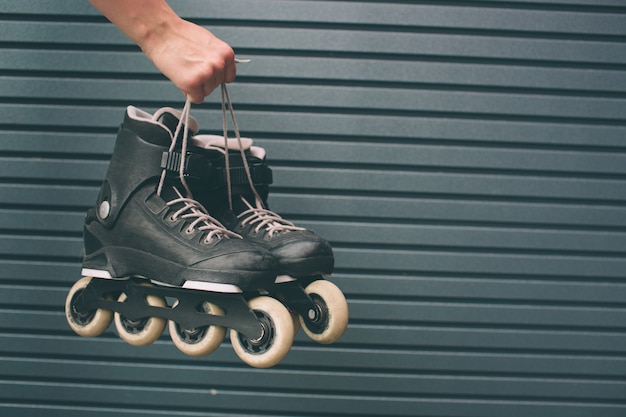 Jolie fille blonde tenant des patins à roulettes à l'extérieur