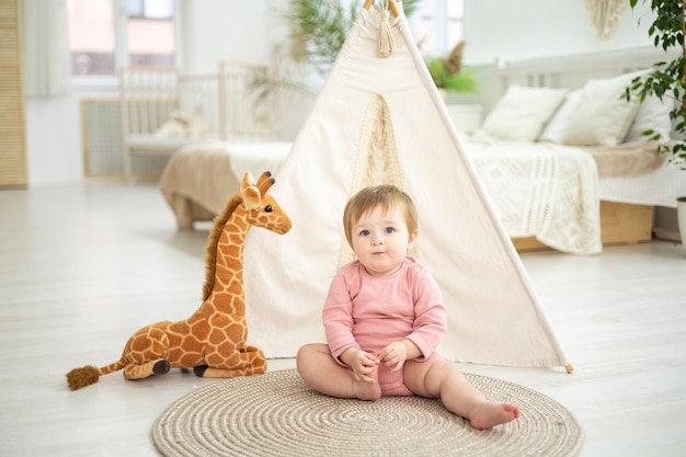 Jolie fille en bonne santé jouant dans le salon de la maison près du wigwam avec des jouets