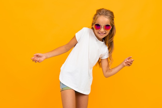 jolie fille brillante dans des verres dans un t-shirt avec une mise en page sur un mur orange