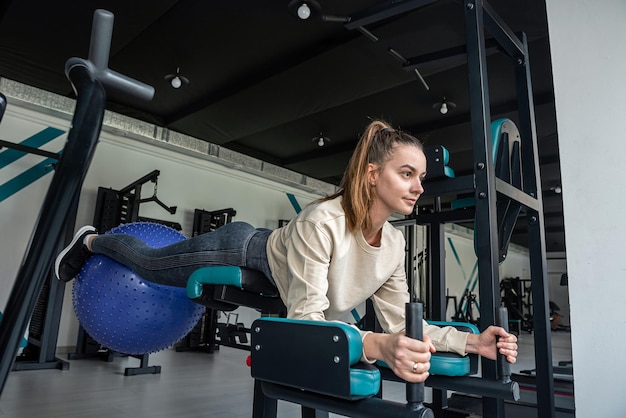 Jolie fille brune fait des exercices sur le simulateur pour entraîner son corps Formation Crossfit et powerlifting Concept de remise en forme sportive