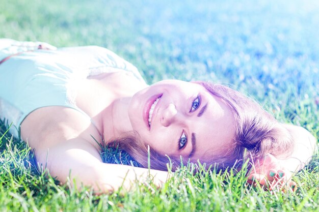 Jolie fille brune portant une robe élégante relaxante en plein air dans l'herbe verte et sent le citron aromatique ou les agrumes de citron vert