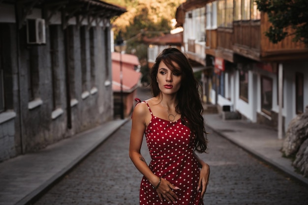 Jolie fille brune avec une silhouette sexy pose sur une belle rue européenne ancienne avec des pavés