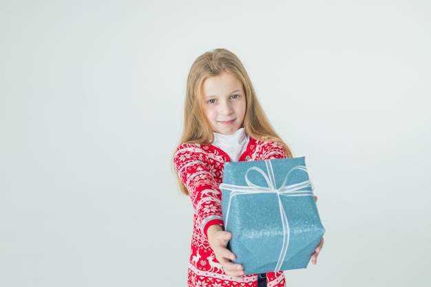 Jolie fille avec cadeau de Noël Enfant mignon, enfant porte un chandail nordique tricoté rouge tenant un cadeau