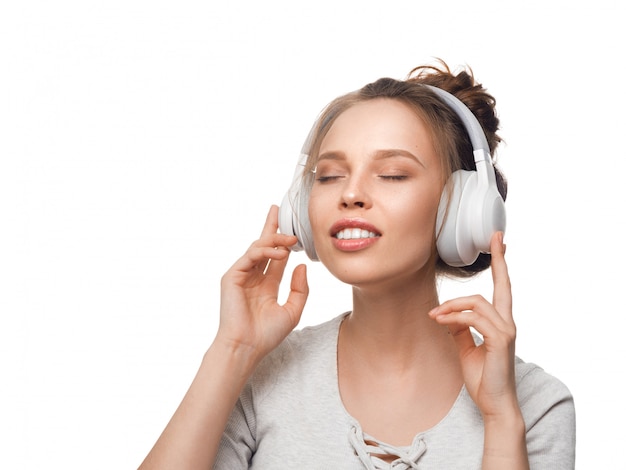 Jolie fille avec un casque sur mur blanc