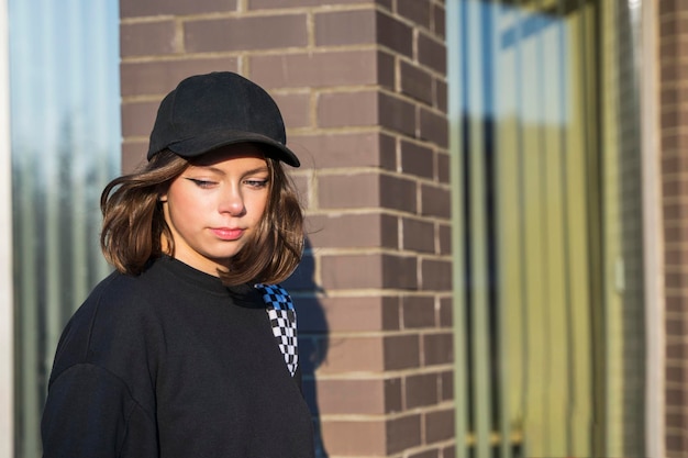 Jolie fille caucasienne effrontée à la mode vêtue d'une casquette de baseball noire à la mode et d'un sweat-shirt noir