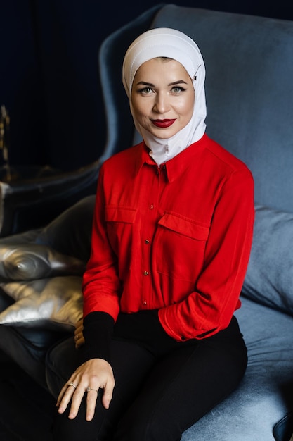 Une jolie fille caucasienne musulmane portant un foulard est assise sur le canapé. religion islamique.