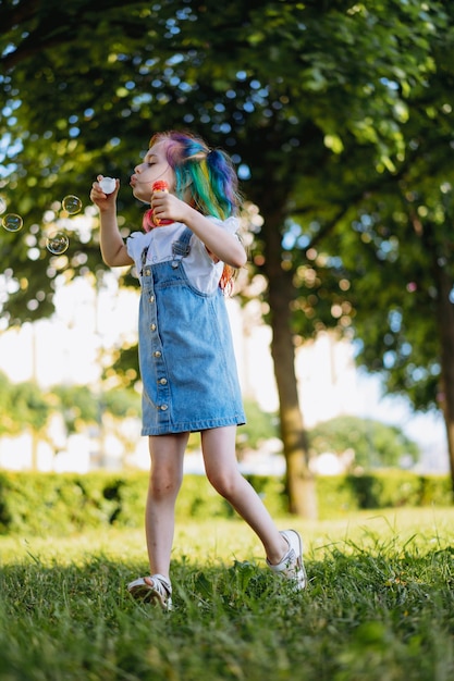 Jolie fille caucasienne s'amusant sur l'anniversaire de la fille faisant des bulles dans le parc