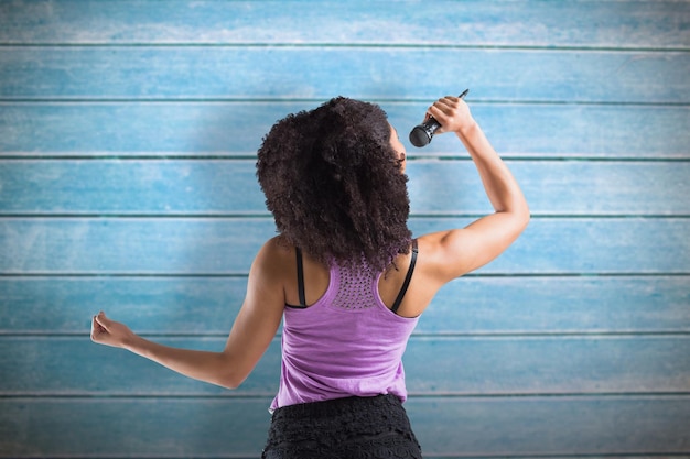 Jolie fille chantant contre des planches de bois