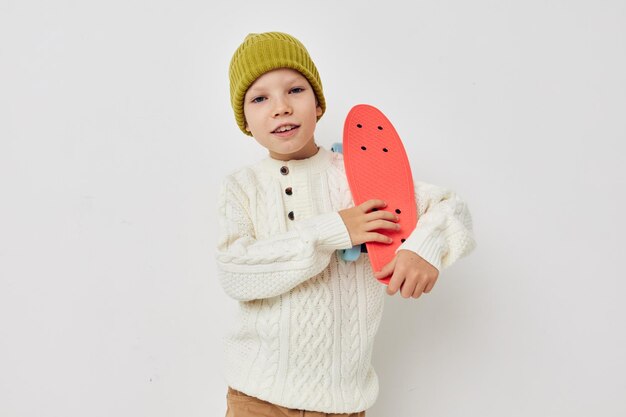 Jolie fille en chapeaux avec une planche à roulettes dans les mains fond clair