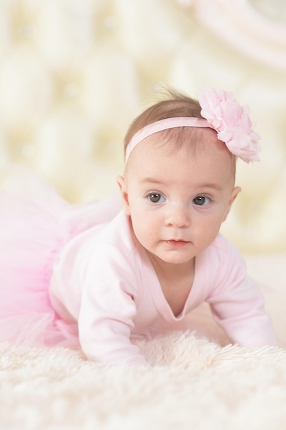 Jolie fille charmante en robe rose sur le lit à la maison