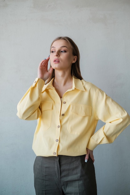 Jolie fille en chemise jaune au mur de béton