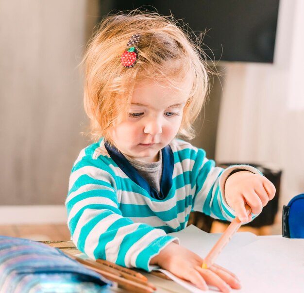 Une jolie fille avec un crayon à la maison.