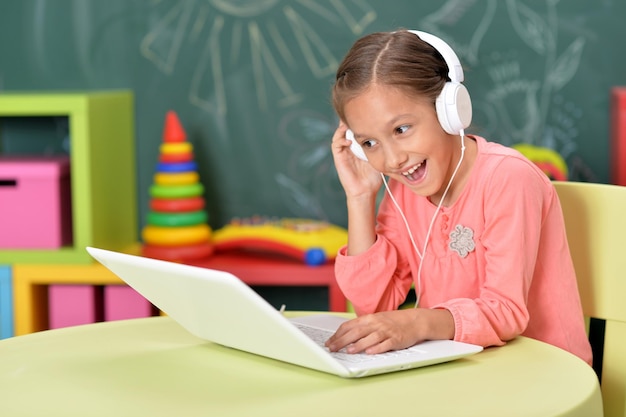 Jolie fille dans un casque à l'aide d'un ordinateur portable en classe