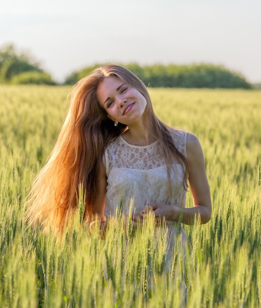 Jolie fille dans un champ au coucher du soleil