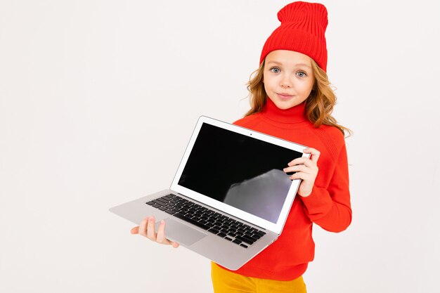 Jolie fille dans un chapeau rouge montre un écran d'ordinateur portable