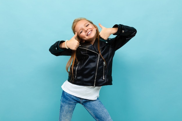 Jolie fille dans un look décontracté avec une veste en cuir et un jean montre la classe sur un fond bleu clair.